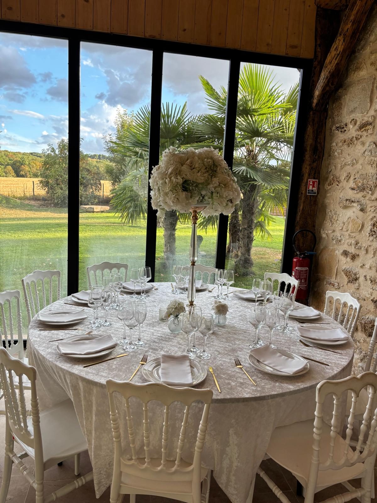 Table de réception avec vaisselle et verrerie louées en Essonne, face aux baies vitrées du domaine